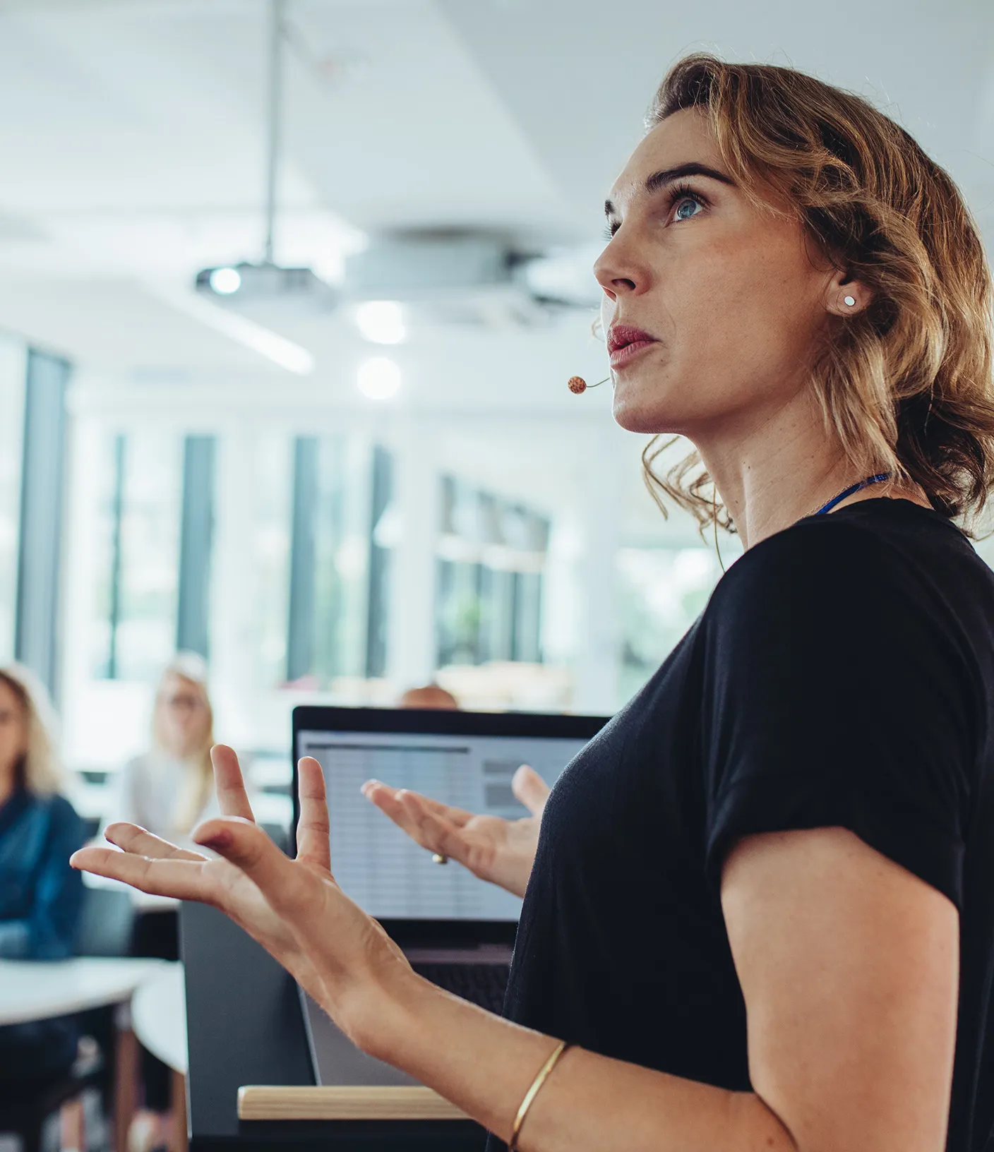 Frau h&auml;lt einen Vortrag vor einer Gruppe von Menschen und schaut auf die Folien